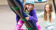 Kids smiling and playing on a playground.