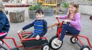 Preschoolers ride red tricycles