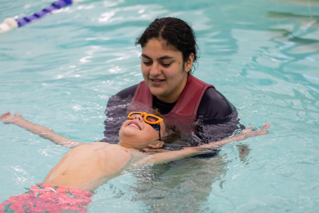 A woman teaches a young boy how to swim.