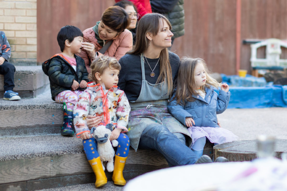 A woman sits with two preschoolers.