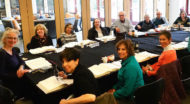 A group sits around a table reading and discussing the Torah.