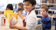 Young boy smiling while glazing a bowl.