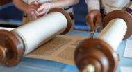 Image of the Torah unrolled on a table being read.